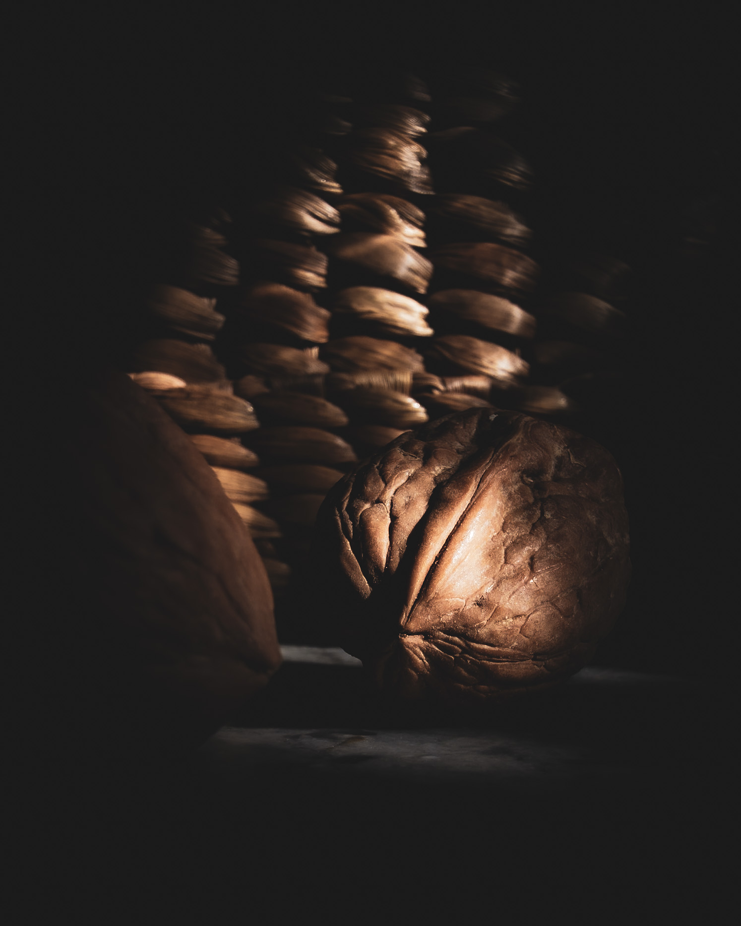 Close-up of a walnut in warm light and shadow with a softly blurred basket in the background.